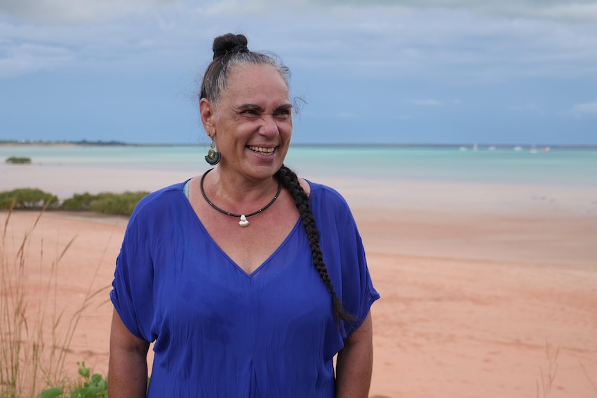 Trudi stands on the beach, laughing.