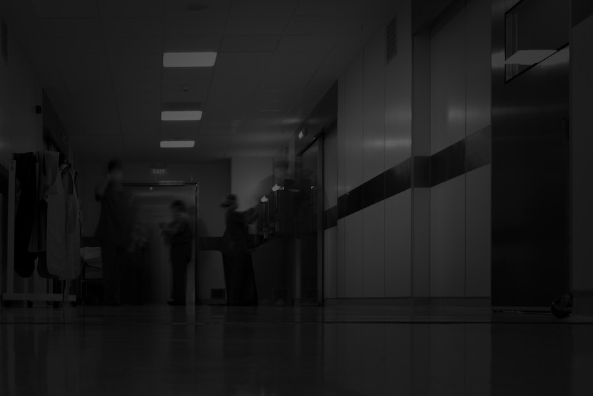 A stock photo of a dark hospital corridor, edited so it's in black and white.