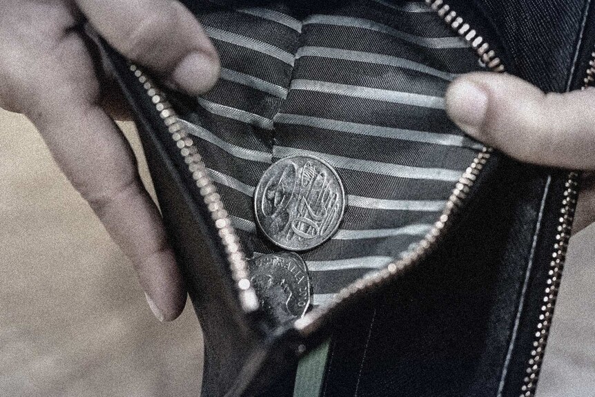 A woman holds an wallet open to show some silver coins.