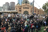 Large crowd of people outside Flinders St Station in Melbourne.