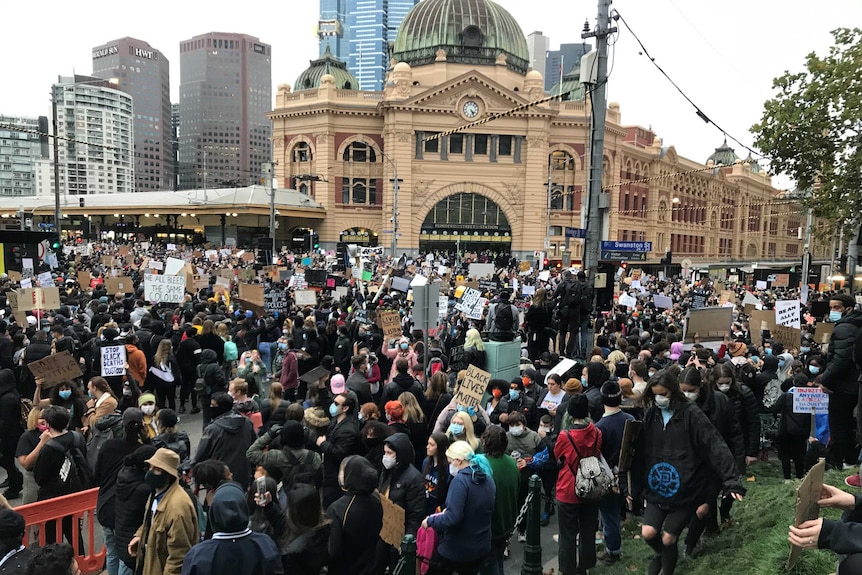 Large crowd of people outside Flinders St Station in Melbourne.