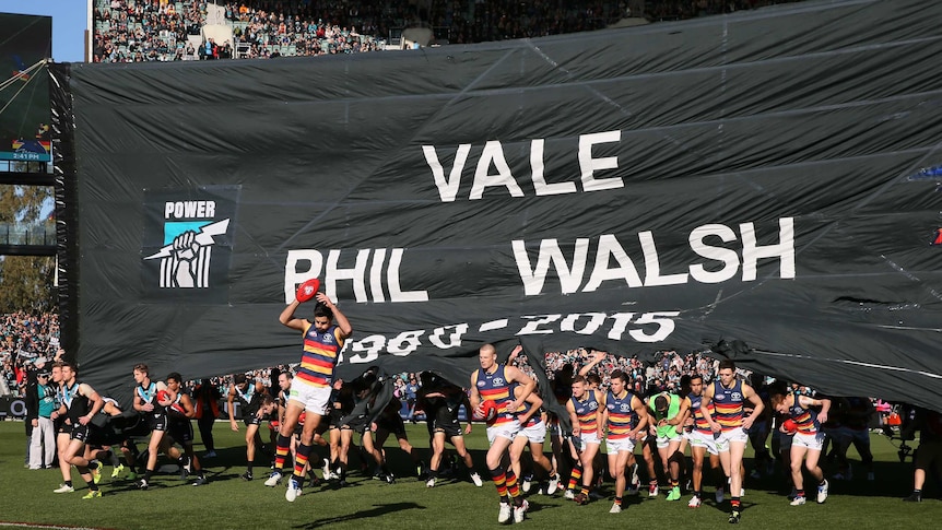 Crows and Power players run through the same banner before play at Adelaide Oval on July 19, 2015.