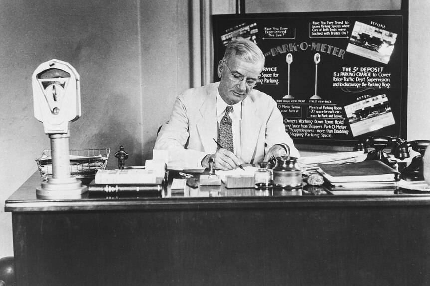 A black and white photo of a man sitting at a desk.