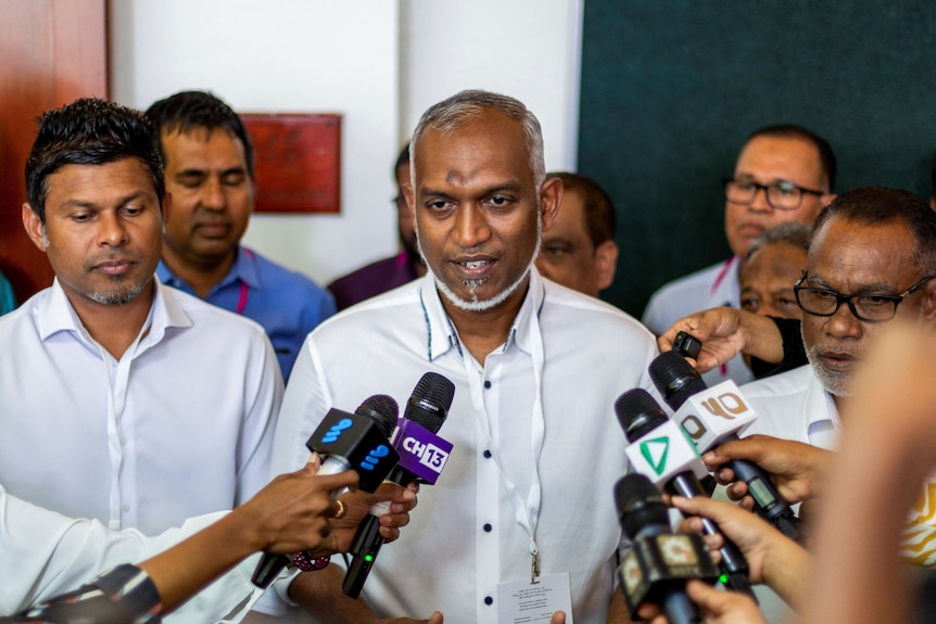 man faces microphones pointed at him