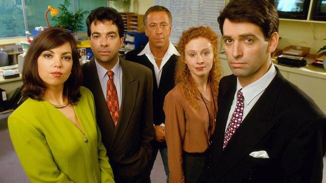 three men and two women dressed as newsreaders in a promotional photo in an office