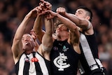 Collingwood and Carlton players compete in a pack for a mark