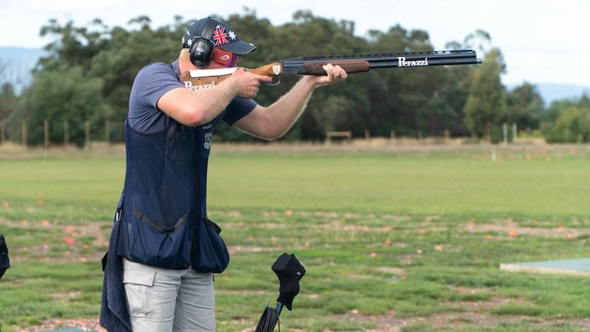 Man holding a large gun in a paddock at a qualifying event.