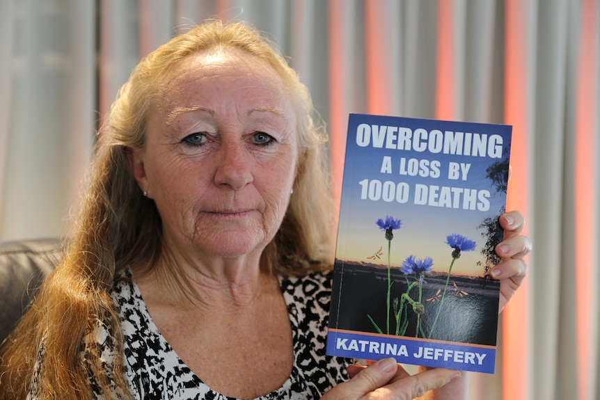 Katrina Jeffery holds her book Overcoming A Loss By 1000 Deaths