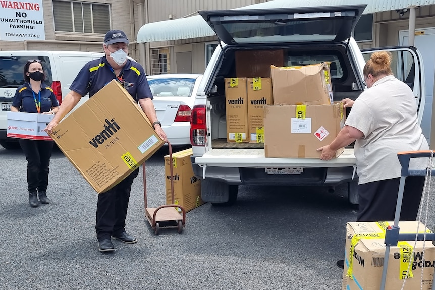 Health unit officers load a van with boxes allegedly containing illegal tobacco products
