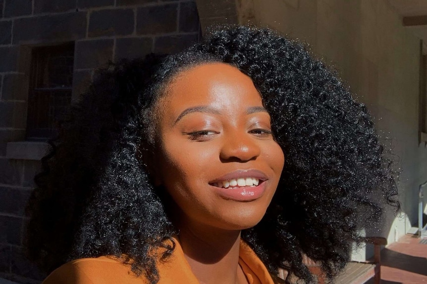 A young woman looks at the camera in a selfie and smiles