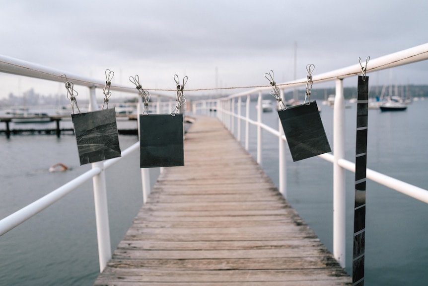 Outside on a small jetty, a photographer hands negatives on a string to dry them.