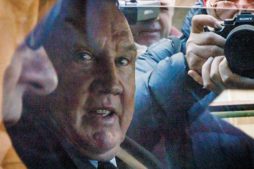 Middle aged man close up in car, photographer in background