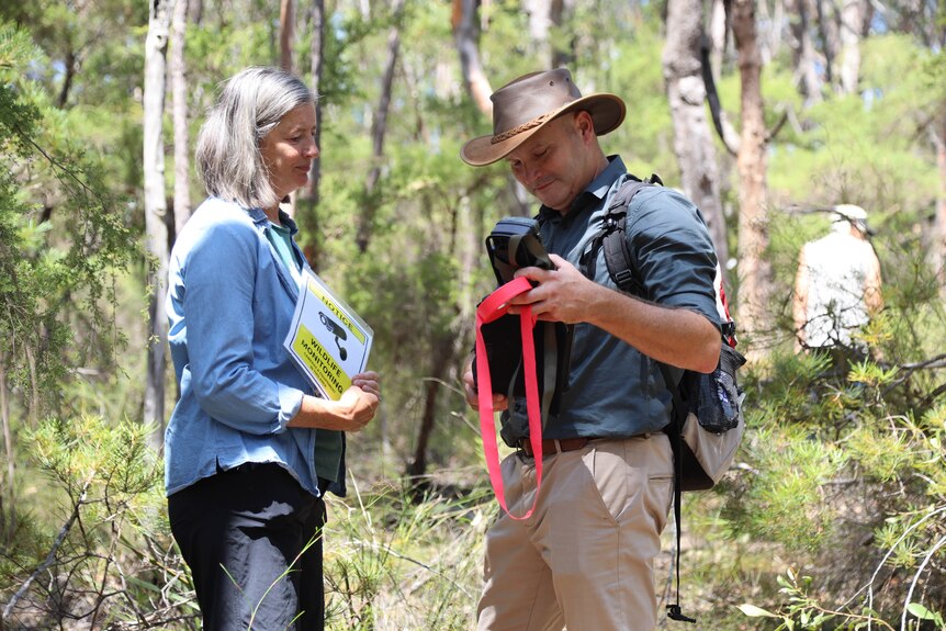 a man and woman holding tools standing in bushland