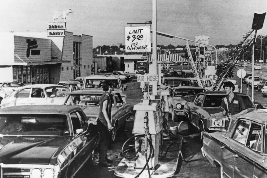 A black-and-white image of cars queued at a pump reading "limit $3 per customer"