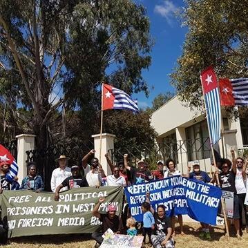 Protestors wave flags and signs outside the Indonesian Embassy in Canberra.