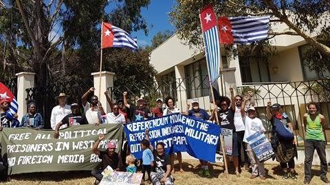 Protestors wave flags and signs outside the Indonesian Embassy in Canberra.
