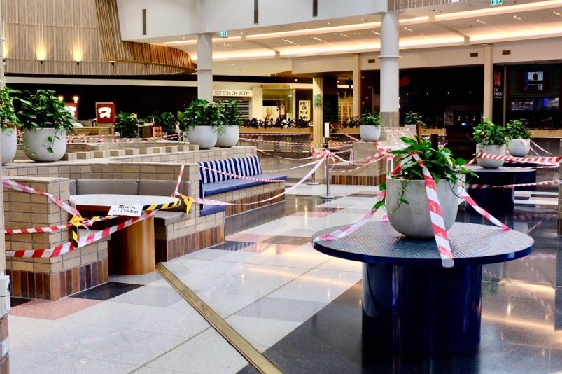 A shopping centre foodcourt is covered with red and white tape, yellow and black tape and a sign saying 'area closed'