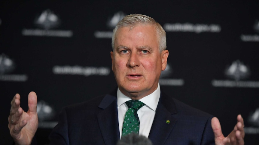 Michael McCormack gestures with both hands at a press conference.