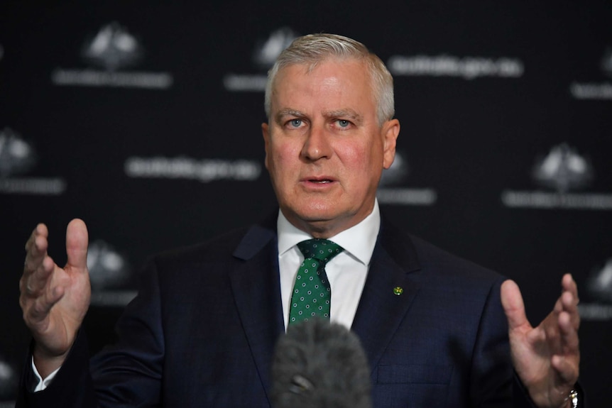Michael McCormack gestures with both hands at a press conference.