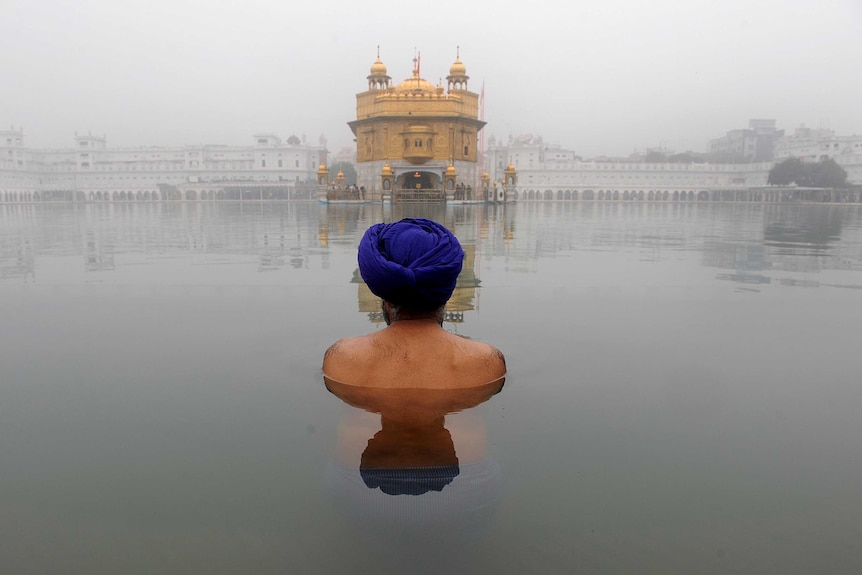 A Sikh man bathes in front of the Golden Temple in Amritsar