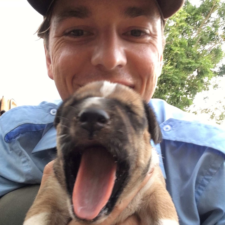 Man in cap with yawning puppy