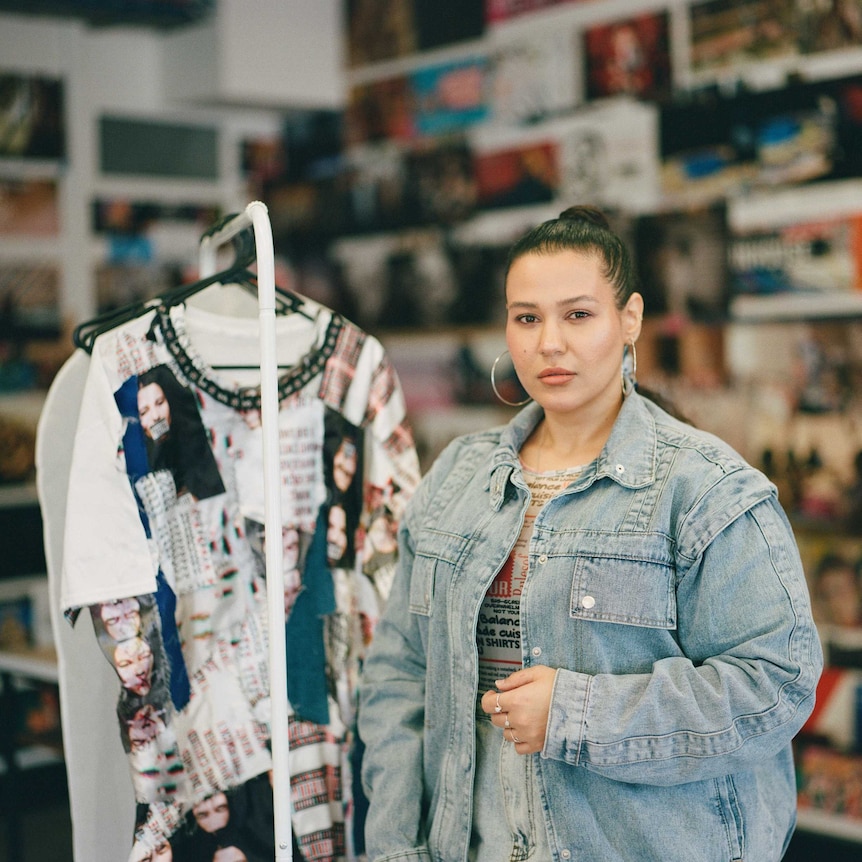 Ginan Tabbouch stands next to a clothes rack.