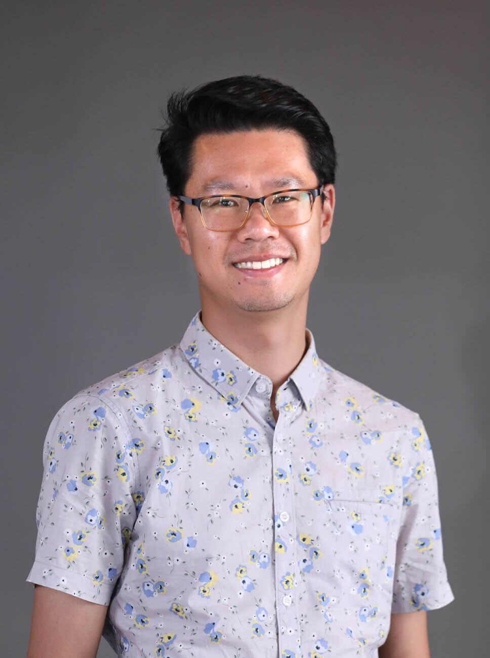 headshot of a man smiling at camera and wearing glasses.