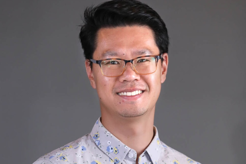 headshot of a man smiling at camera and wearing glasses.