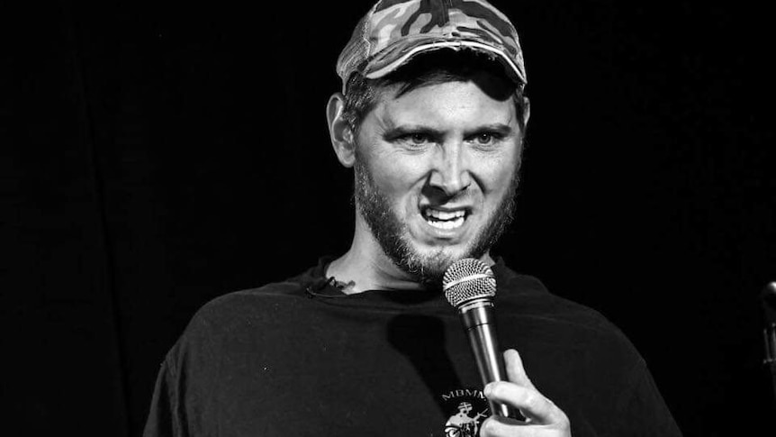 Black and white photo of a man holding a microphone and making a strange face