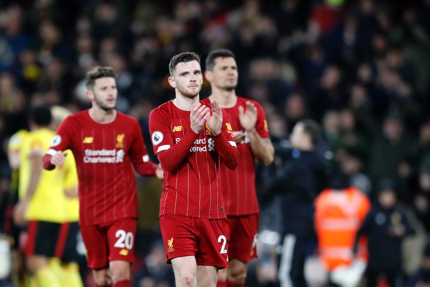 A dejected looking footballer claps his hands as he walks off the ground after a game.