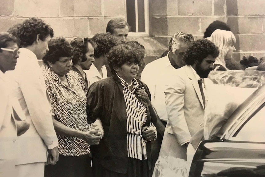 Archival images of Mark's funeral, the family walking the casket to the hearse.