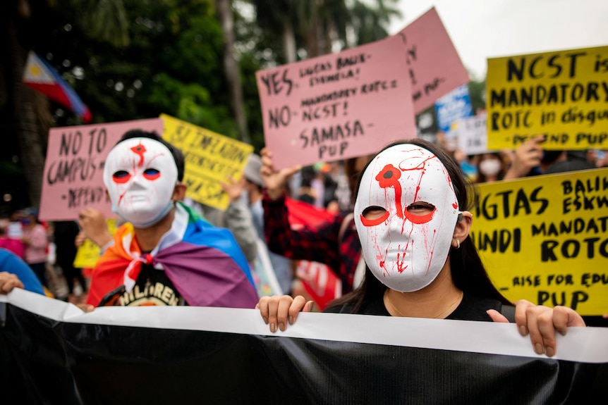 Filipino activists wear masks painted with a bullet wound