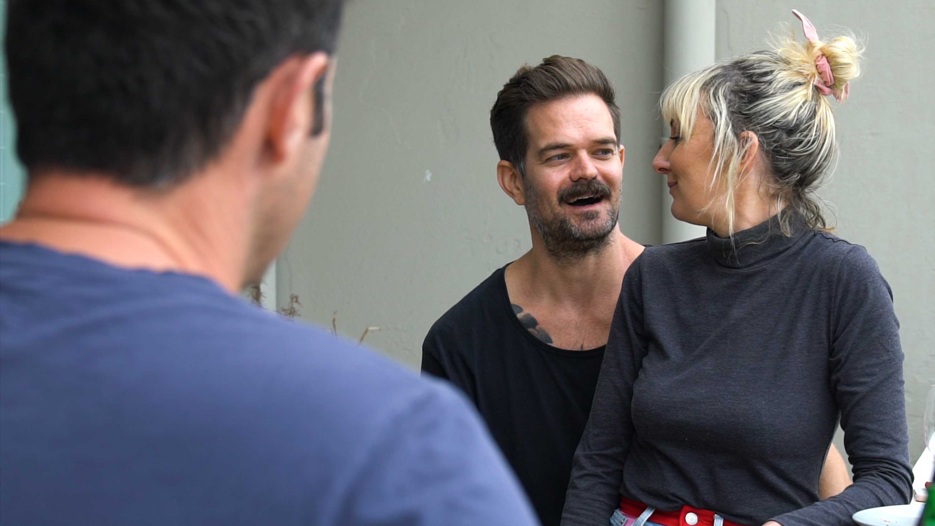 A woman sits on her male partner's lap as they chat with friends at a weekend barbeque for a story about assisted reproduction.