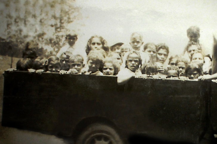 Aboriginal students in the back of a 1930s pick up truck the teacher used to take them to school.