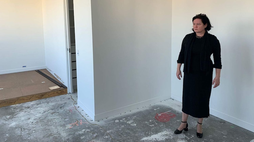 Unit owner Louisa Carter stands in her bedroom in her unfinished Spring Hill apartment.