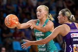 A Super Netballer passes the ball away from her body as opposition player reaches out to stop her.