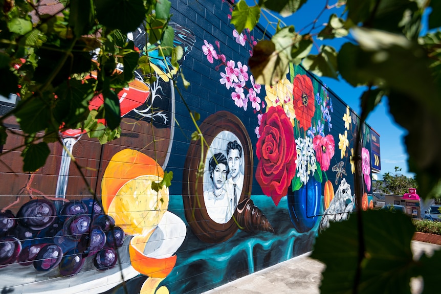 A brightly coloured mural of a still life scene, painted on the side of a building in a suburban area.