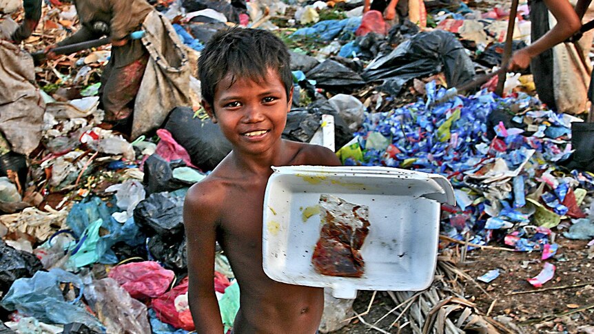 A boy shows off his find at a Cambodian rubbish dump