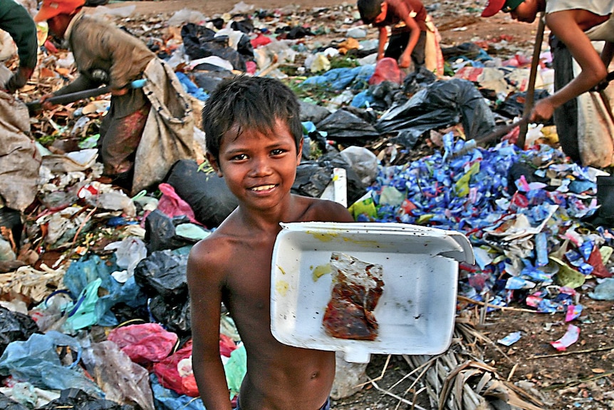 A boy shows off his find at a Cambodian rubbish dump