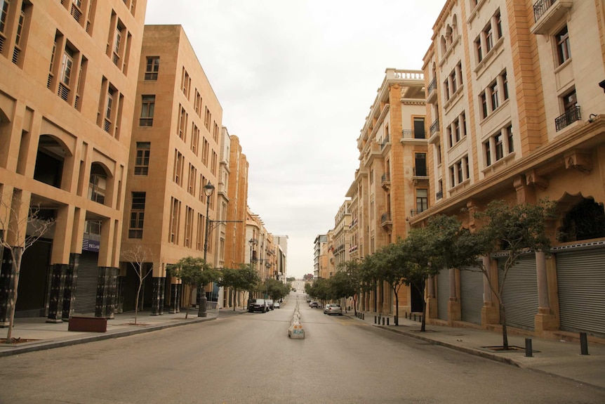A line of sandstone buildings sit on either side of an empty street.