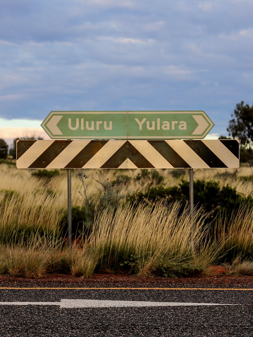 A road sign pointing in one direction to Uluru and the other to Yulara