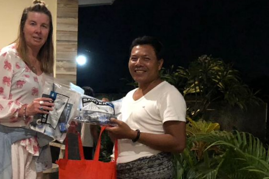 Susan Lock hands over water filters to an Indonesian local in Bali