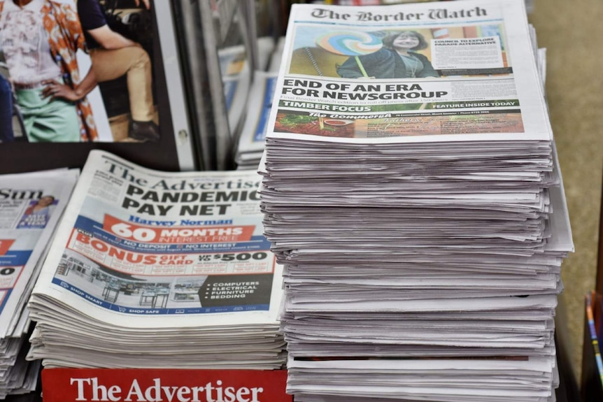 A tall stack of newspapers The Border Watch sit on a wooden counter