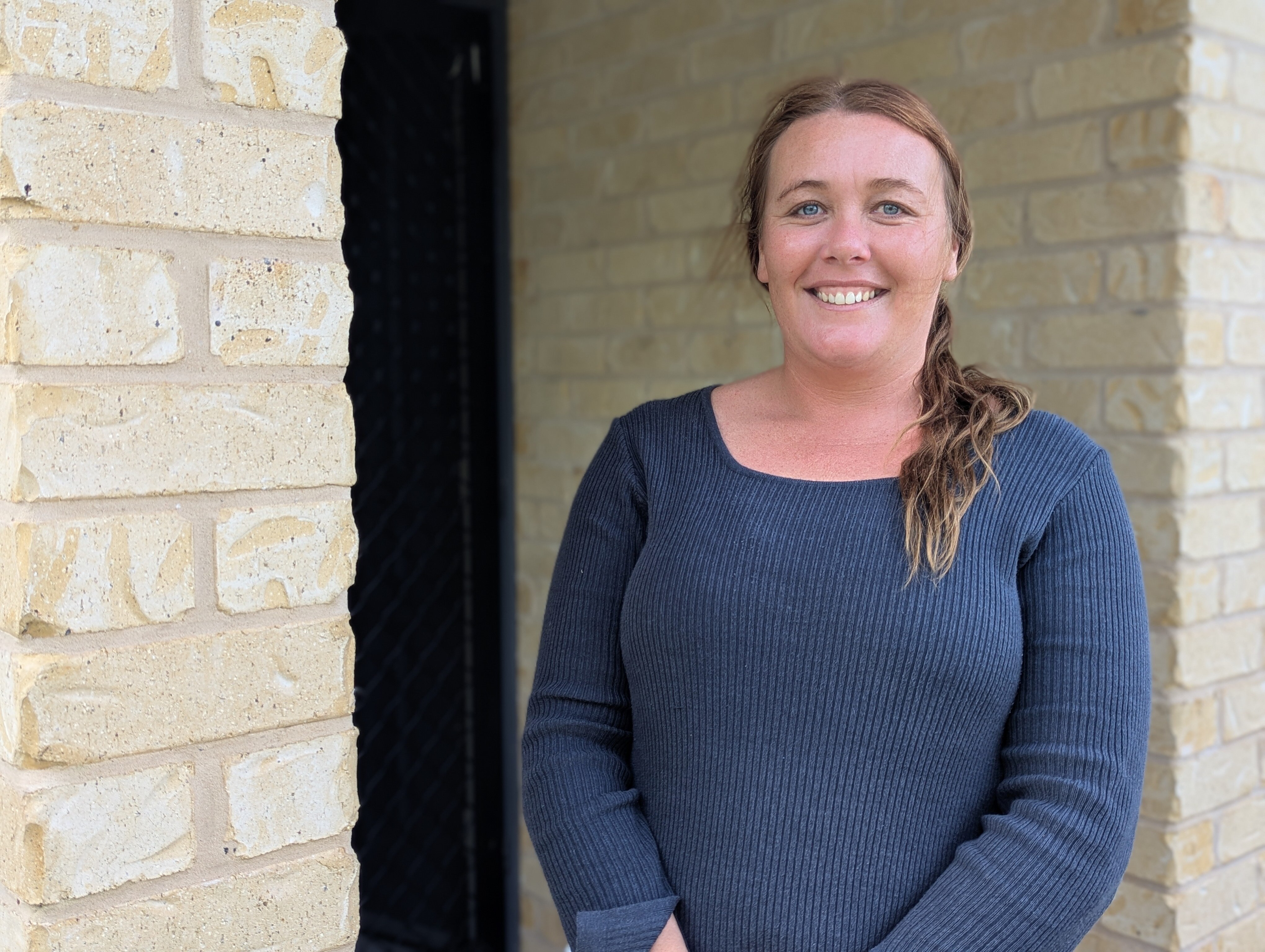 Woman stands at front door.