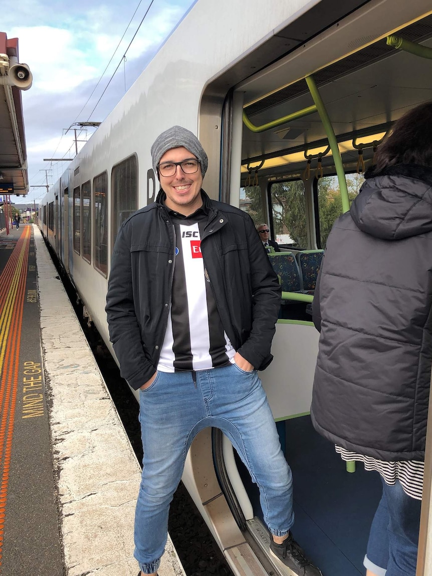 Max Walton standing at a train station in Melbourne ready for an AFL game for story on domestic winter holidays