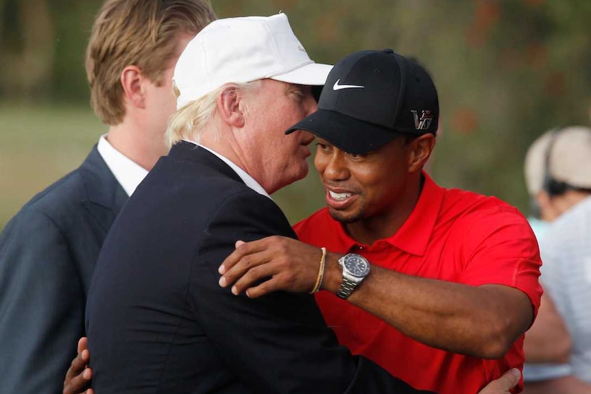 Donald Trump embraces Tiger Woods and speaks into his ear