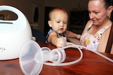 Raelene Edmundson with her one-year-old son Jayden grabbing a breast pump on the table.