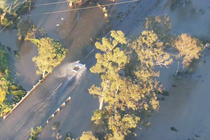 A car driving along flooded Bowhill Road at Willawong, as seen from traffic helicopter