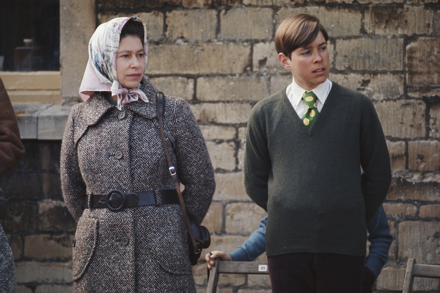 A young Queen Elizabeth II, wearing a scarf tied around her hair and secured under the chin, with then-teenaged Prince Andrew