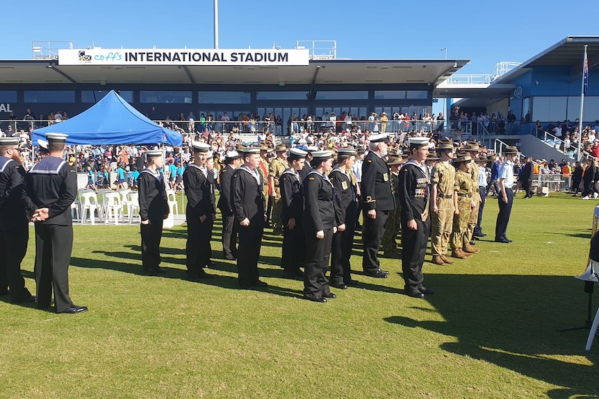 People in military dress at a sports stadium.